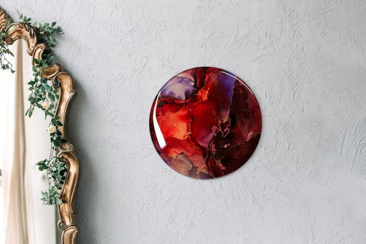Round abstract painting on a wall next to a mirror. Maroon, red, purple and copper art that portrays endings and beginnings before we are reborn. Transformation symbolism based on the arcana death card meaning and Phoenix rising by inkandescent Arts.