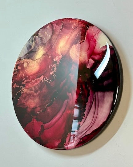Round decorative abstract wall art featuring red black and gold.