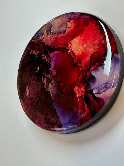A small wall art creation in red and purple. Circular and ready to hang it is small but mighty. Ready to draw the eye and entrance with its beauty and colour.