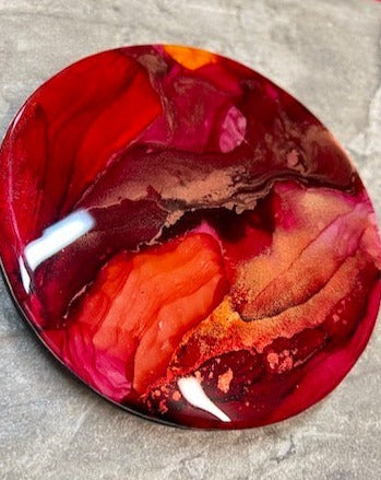 An expression of reawakening  the life-force within.  Resin, abstract fluid art painting featuring tones of deep red, orange-red, metallic copper and gold.  Wall art by Inkandescent Arts. Original resin red abstract wall art expression. CIRCULAR WALL PAINTING. RED WALL ART. ART FOR THE HOME.