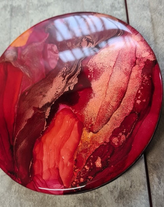 An expression of reawakening  the life-force within.  Resin, abstract fluid art painting featuring tones of deep red, orange-red, metallic copper and gold.  Wall art by Inkandescent Arts. Original resin red abstract wall art expression.  WALL ART. ART FOR THE HOME. CIRCULAR WALL PAINTING.