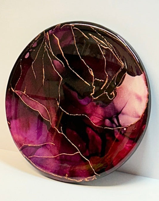 Resin wall art abstract vision. An original painting full of jewel tones of dark purple and red-violet that saturate. Veins of metallic copper branch out atop the heated colours, adding another layer to the elemental energy expressed in this artwork. Size: 10" circular artwork with float effect. Beautiful luxury art  by Inkandescent Arts. Holds themes of divine femininity. Original resin red abstract wall art expression. RESIN ABSTRACT WALL ART.