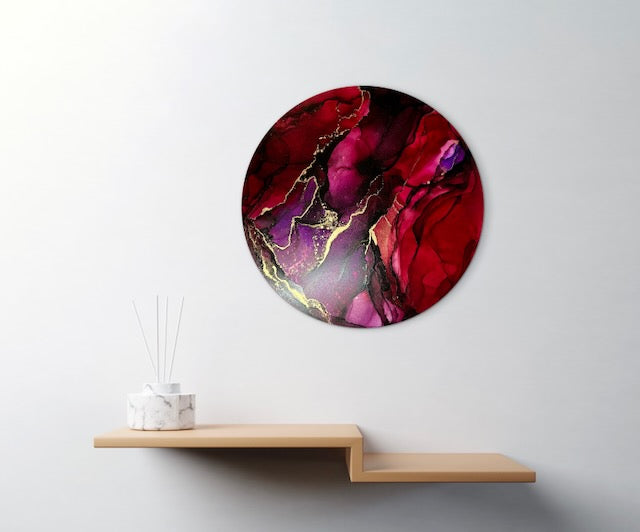 Red purple and brass artwork in a hallway wall above a shelf.  This circular art is an abstract expressionism and is symbolic of rebirth and transformation where we rise from our season of darkness and find better things in the future.