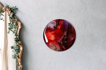Round abstract painting on a wall next to a mirror. Maroon, red, purple and copper art that portrays endings and beginnings before we are reborn.  Transformation symbolism based on the arcana death card meaning and Phoenix rising by inkandescent Arts. 