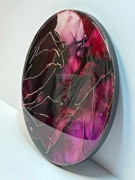 Room decoration in rich, deep red and purple colours dominate this abstract painting. Rebirth symbolism circular art  with a glossy, mirror like surface.

