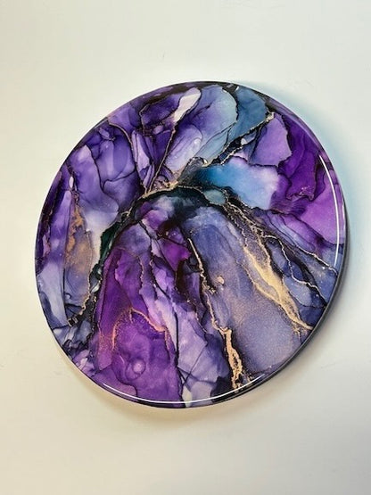Purple and metallic handmade resin art in a round formation.