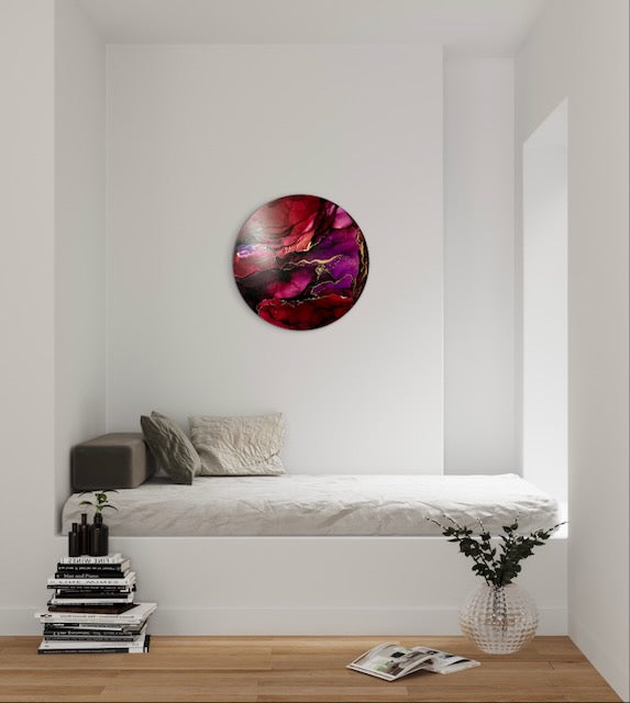 A 10 inch round, abstract painting on a white wall, over a bed in a modern bedroom interior, Featuring red, plum and brass it adds a mystical and energetic feel to to your room.  Original abstract art with symbolic meaning of rebirth and new beginnings by Inkandescent Arts