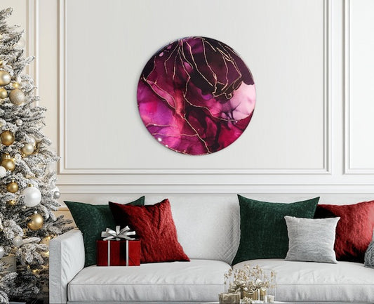 A round burgundy red painting, with copper leaf lines, hung on a neutral coloured wall above a sofa - Symbolic abstract painting of the phoenix rising.