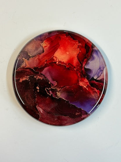 Close up of circular artwork in violet, fiery red, metallic copper, and purple. Modern abstract art that delves into themes of the Phoenix and the death card. A life and death symbol revolving around rebirth, renewal and transformative healing by Inkandescent Arts.