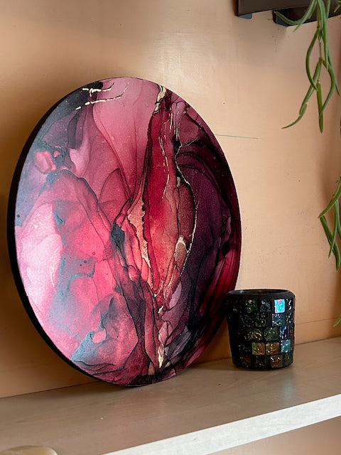 Contemporary abstract art of red and real 23k gold leaf. Displayed at an angle on a shelf in a living room It shows an alternate orientation. Art that signifies a major change by Inkandescent Arts.