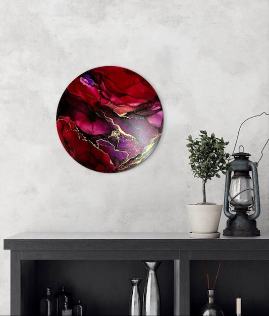 Round, red and purple abstract art for sale  on a living room wall above a dark cabinet. Abstract artwork portraying the death card and phoenix rising  - symbols of rebirth, strength and transformation by Inkandescent Arts
