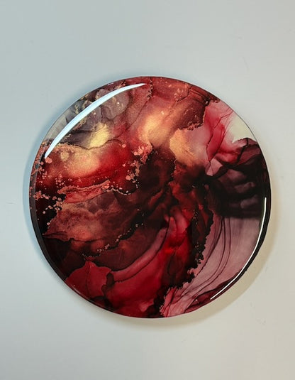 Round red artwork on a white wall - an abstract expressionism of transformation and rebirth in rich red colours.
