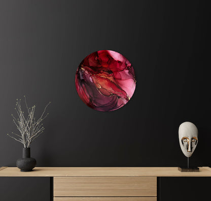 Red garnet art on a black wall above a games console and vase. A rebirth symbol in a round painting of the cycle of change.