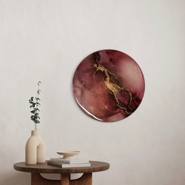 Round decorative wall art adorns a  hallway featuring a maroon and gold design, over to a small table with a vase and books. Modern painting for cosy home interiors.