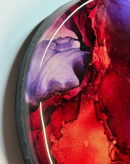 A close up section of ‘Planes of Passion,’ an abstract fluid painting featuring tones of red, violet and maroon with a resin finish. Copper details appear throughout.. Wall  ornament by Inkandescent Arts.