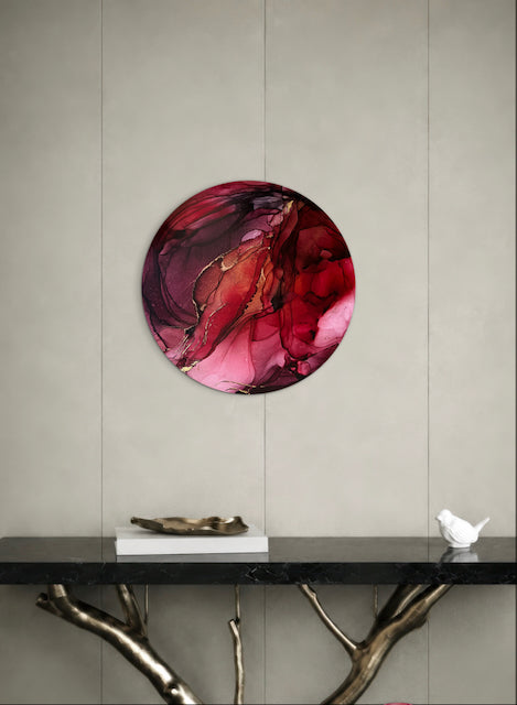 Abstract artwork in red on an interior wall above a black shelf. A symbol of new beginnings in a round art piece.