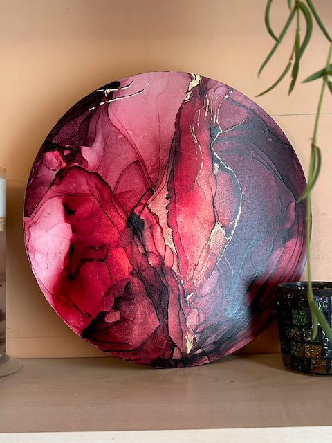 A fiery red, original abstract painting for sale on a shelf with candle holder and plant. Small art symbolising moving on based on the death card by Inkandescent Arts.