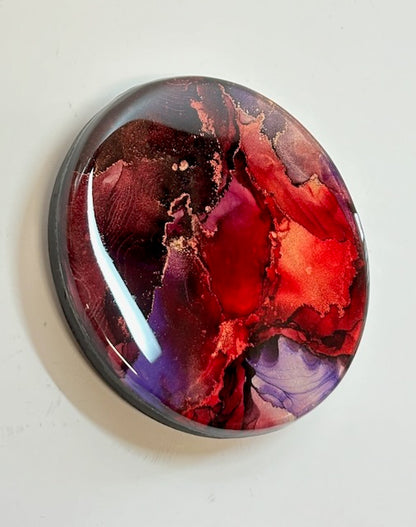 Original abstract artwork for sale displayed at an angle. This small painting of mystical purple, warm red and metallic has phoenix symbolism at its core and is a representation of rebirth  - A visual metaphor by inkandescent Arts.