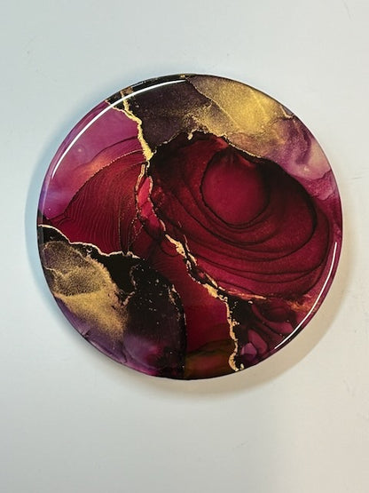 A circular abstract painting showing depth and colour details of red and gold lines and fades. Silken shine and deep colour highlight the fluid forms of this luxury artwork. Symbolism art that examines the duality of fire - by Inkandescent Arts.