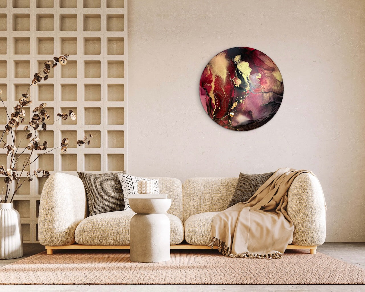 Gold red and black wall art on a living room wall with a beige sofa, decorative pillow and ornaments. An original artwork of a 10 inch round; abstract symbolism of rebirth and passion.