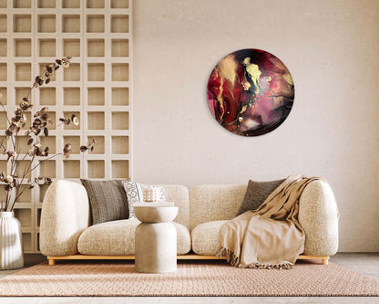 Gold red and black wall art on a living room wall with a beige sofa, decorative pillow and ornaments. An original artwork of a 10 inch round; abstract symbolism of rebirth and passion.