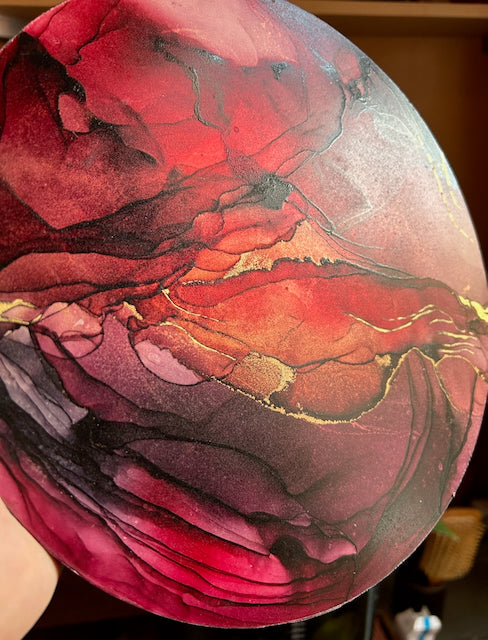 Witch art in scarlet, red, burgundy and real gold leaf, held up by a hand, showing beautiful layering of depth and colour.