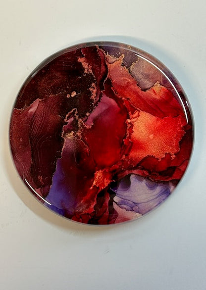 Close up of small wall art, showing metallic lines amongst red and violet colours. Rebirth symbolism in a round abstract painting by Inkandescent Arts.