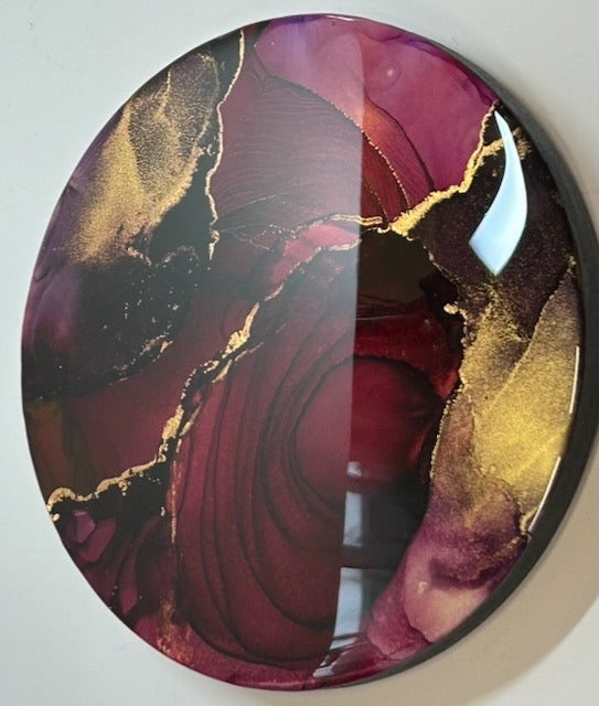 Modern painting for sale in a round abstract design displayed slightly angled. Featuring deep red, black and rich gold, topped in a glossy, luxury shine. Rebirth artwork and strength symbol by Inkandescdent Arts.
