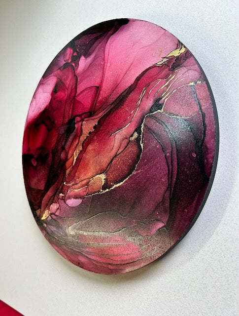A symbol of life and death derived from phoenix fire bird and the death card in fortune telling, oracle sets and tarot cards. Representing changes - rebirth and new beginnings. Circular artwork at an angular view showing a closer look of 23kt gold leaf accents over burgundy and red colours; lines and swirls incorporate the abstract painting adding depth and tone. Artwork by Inkandescent Arts.