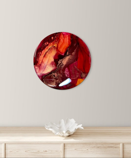A round painting displayed on a wall above a mantle and ornament. This tarot themed art holds the death card meaning of life and death and represents the major events that transform us. Abstract art by Inkandecsent Arts.