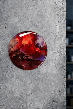 Round art of scarlet and violet adorns a grey wall. Transition art from death to rebirth and new beginnings in abstract art by Inkandescent Arts.